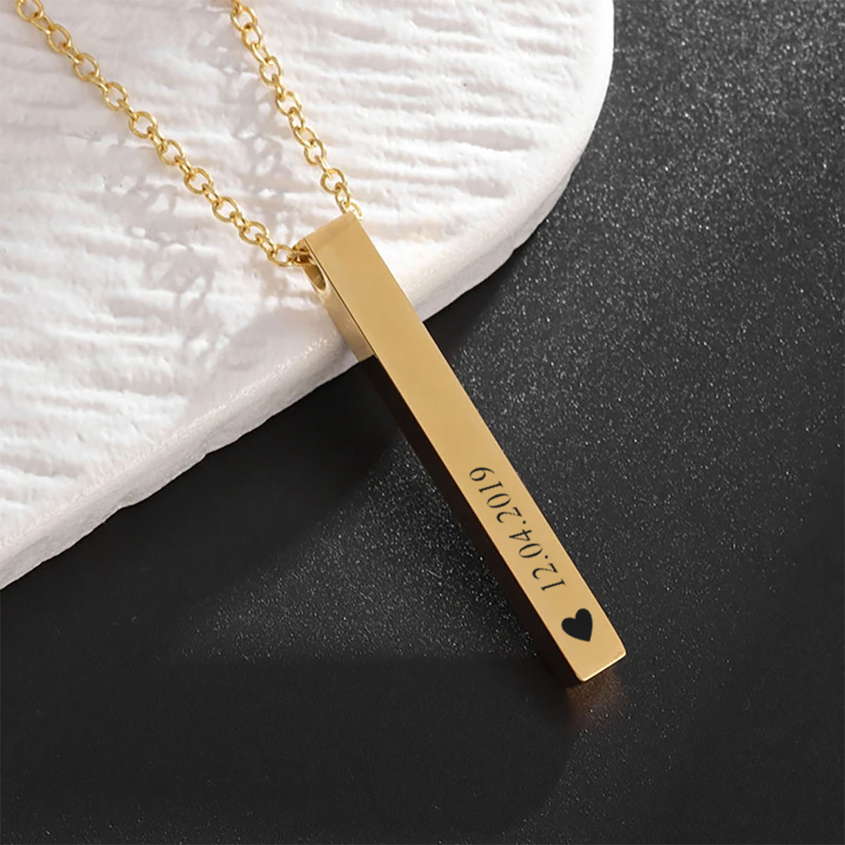 Złoty naszyjnik z pionową zawieszką typu sztabek z grawerem daty i symbolem serca – elegancka biżuteria personalizowana na prezent.